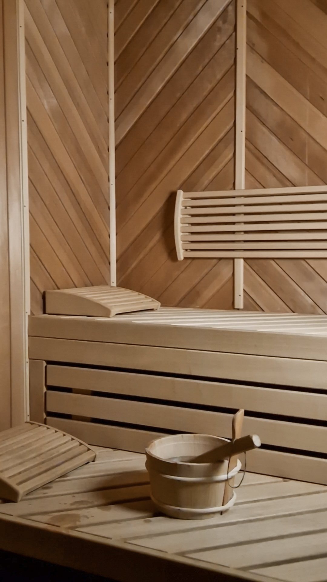 Finnische Sauna mit hellen Holzbänken und Aufgusskübel